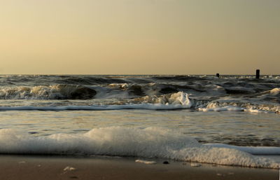 Waves rushing towards shore against clear sky