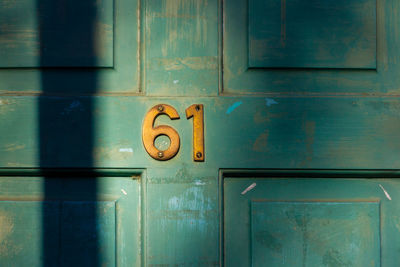 House number 61 on a turquoise wooden front door in london