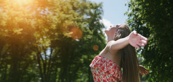 Side view of woman standing against trees