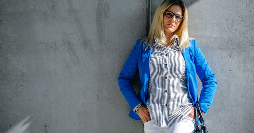 Portrait of smiling young woman standing against wall