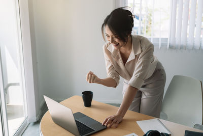 Young woman using mobile phone while sitting on table