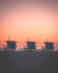 Lifeguard hut on beach against sky during sunset