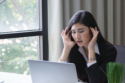 Businesswoman using laptop while working in office