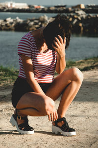 Full length of young woman crouching on street