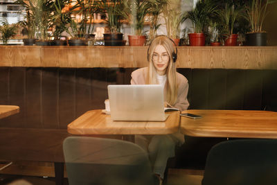 A smiling student wearing glasses and headphones works and studies online using wireless technology