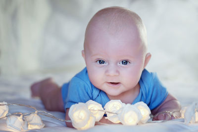 Close-up portrait of cute baby boy with decoration lying on bed