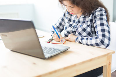 Woman using mobile phone while sitting on table