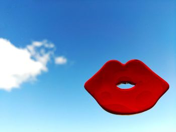 Close-up of red heart shape against blue sky