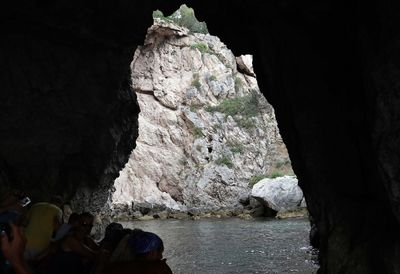 People on rock formation in sea