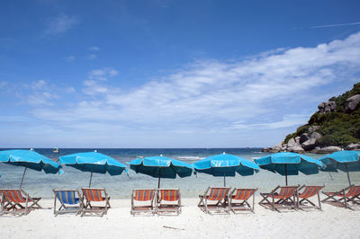 Chairs on beach against blue sky