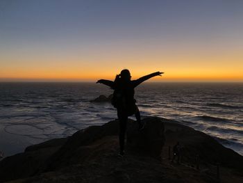 Rear view of person standing on beach during sunset