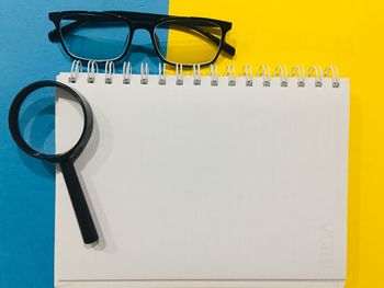 Close-up of magnifying glass on blank book at table