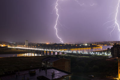 Lightning over illuminated city against sky at night