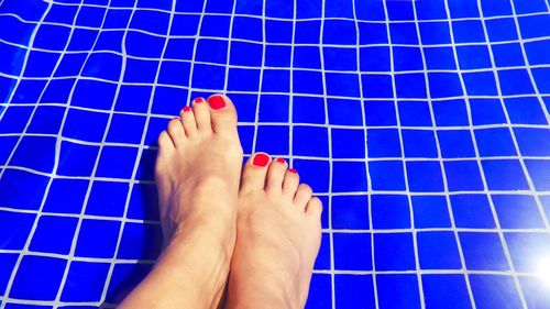 Low section of woman legs against swimming pool