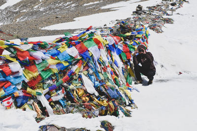 Man photographing in snow by heap of prayer flags