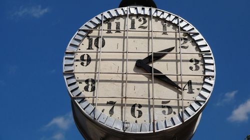 Low angle view of clock against blue sky
