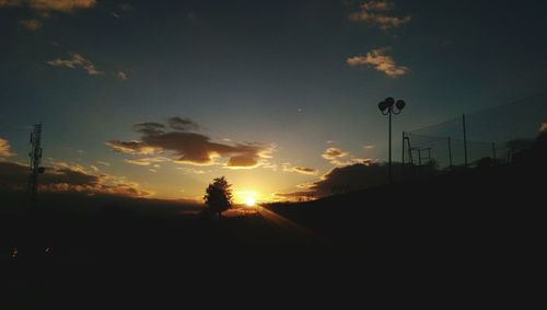 Silhouette street against sky during sunset