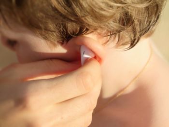 Cropped hand of person putting headphones in boy ear