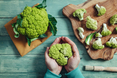 High angle view of hand holding vegetables on table