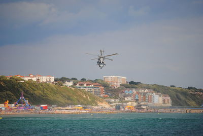 Helicopter flying over sea against sky