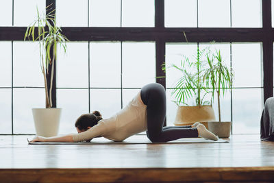 Side view of woman sitting on floor at home