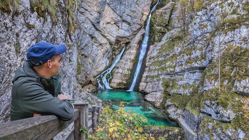 Side view of man on boardwalk by river against mountain