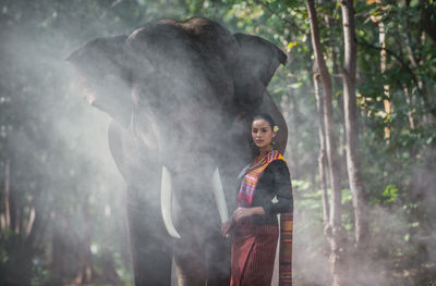 Portrait of smiling woman standing with elephant in temple