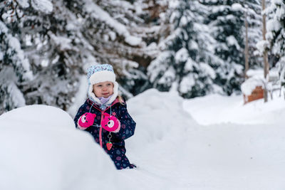 Portrait of smiling boy standing on snow covered field