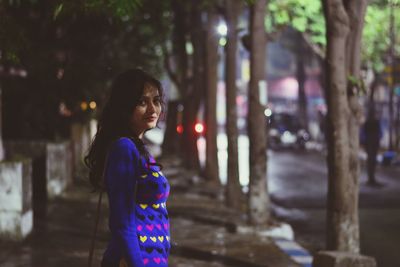 Portrait of young woman standing in city