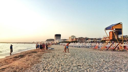 People standing on beach against clear sky