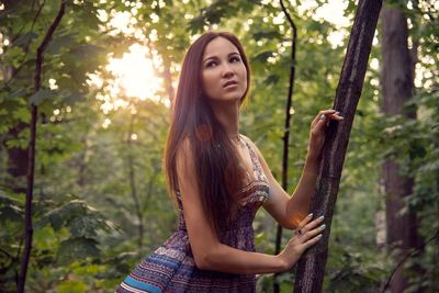 Thoughtful young woman looking away while standing in forest