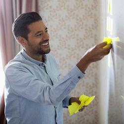 Smiling businessman removing memo notes from whiteboard in office