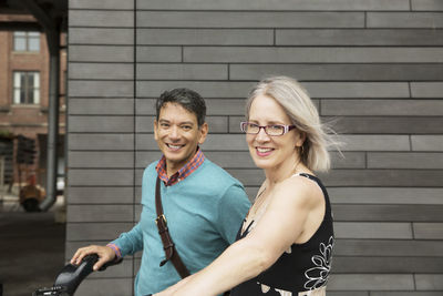 Portrait of happy mature couple standing against wall