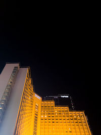 Low angle view of illuminated buildings against clear sky at night