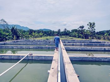 Swimming pool by lake against sky