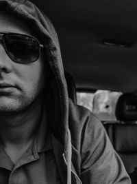 Cropped image of hooded man wearing sunglasses in car