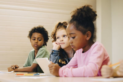 Male and female students looking at digital tablet in classroom