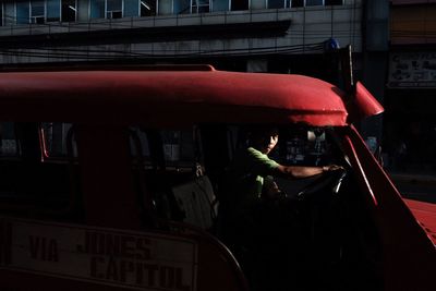 Midsection of woman standing by bus in city