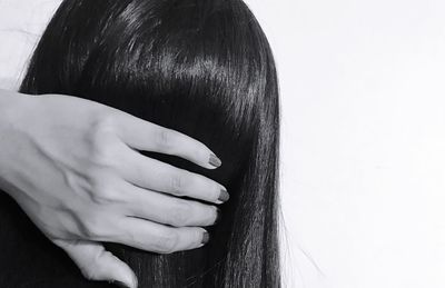 Close-up portrait of woman with hand on white background