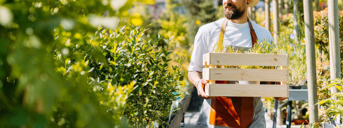 Man gardener holding a box of flowers. e-commerce, online order concept.