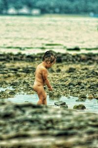 Side view of naked boy walking at beach
