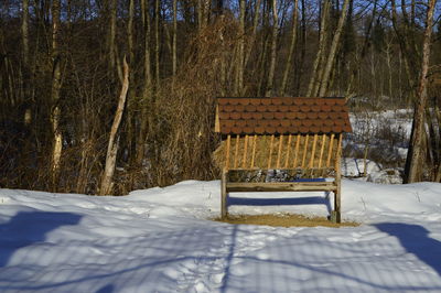 Empty bench on snow covered field during winter