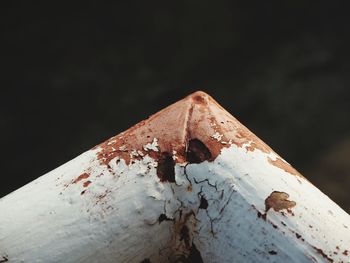 Close-up of rusty metal on wood against black background