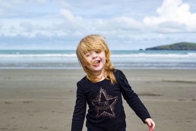 Portrait of smiling young woman standing on beach