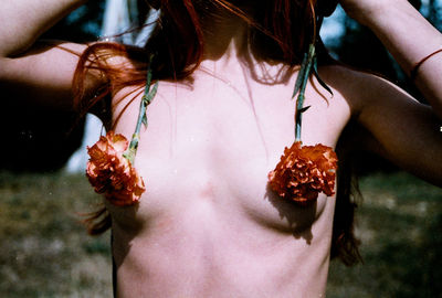 Midsection of sensuous woman with flowers on breasts
