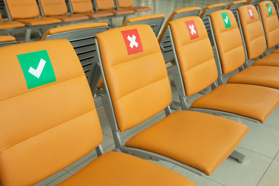 Row chais with the sticker sign indicating sitting position for social distancing in the airport