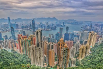 Aerial view of modern buildings against cloudy sky in city