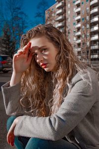 Portrait of beautiful young woman shielding eyes while sitting outdoors