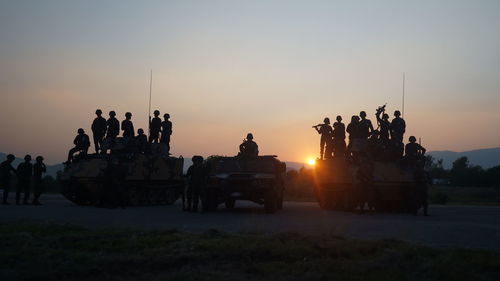 Silhouette soldiers on field against sky during sunset