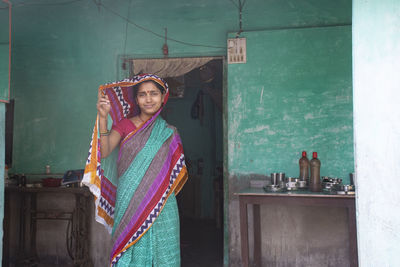 Portrait of smiling woman standing against the wall